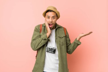 Genç filipinli gezgin adam bir avuç üzerinde kopya alanı tutar, yanak üzerinde el tutmak. Şaşırmış ve memnun.