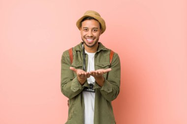 Genç filipinli gezgin adam avuç içi ile bir şey tutan, kameraya sunan.