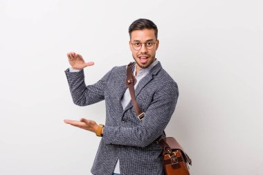 Beyaz bir duvara karşı genç iş filipino adam şok ve elleri arasında bir kopya alanı tutarak şaşırdı.