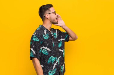 Genç filipinli adam yaz giysileri giyen bağırarak ve açık ağız yakınında palmiye tutarak.