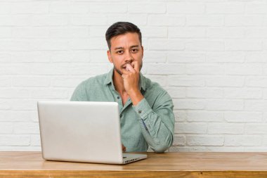 Genç filipinli adam onun laptop tırnakları ısırma ile çalışan oturan, sinir ve çok endişeli.