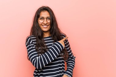 Genç entelektüel hintli kadın gülümseyerek ve bir kenara işaret, boş alanda bir şey gösteren.