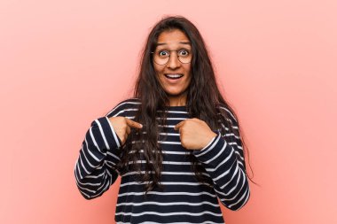 Genç entelektüel hintli kadın kendini işaret şaşırttı, geniş gülümseyerek.