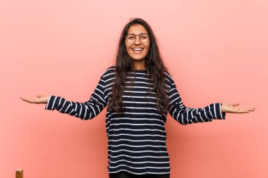 Genç entelektüel hintli kadın kolları ile ölçek yapar, mutlu ve kendinden emin hissediyor.