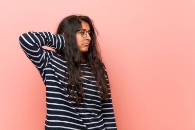 Genç entelektüel hintli kadın başının arkasına dokunarak, düşünme ve bir seçim yapma.