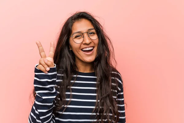 Young intellectual indian woman showing victory sign and smiling broadly.