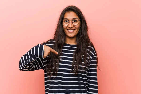 Young intellectual indian woman person pointing by hand to a shirt copy space, proud and confident