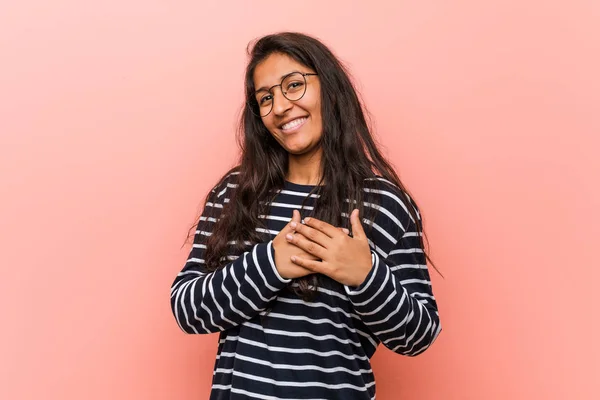 Young intellectual indian woman has friendly expression, pressing palm to chest. Love concept.