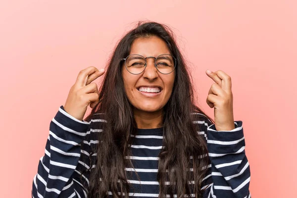 Young intellectual indian woman crossing fingers for having luck