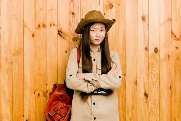 Young chinese traveler woman frowning face in displeasure, keeps arms folded.