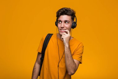 Genç serin öğrenci adam kaygısız ve heyecanlı tezahürat kulaklık ile müzik dinliyor. Zafer kavramı.