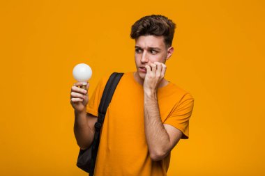 Genç öğrenci adam şans için parmakları geçiş bir ampul tutan