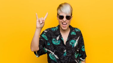 Bir devrim kavramı olarak boynuzları jest gösteren bir yaz bakmak giyen genç kıvrımlı kadın.