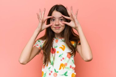 Kırmızı duvara karşı yazlık kıyafetler giyen kız bir başarı fırsatı bulmak için gözleri açık tutarak.