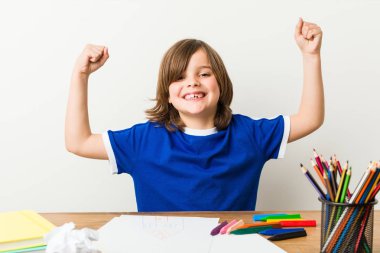 Küçük çocuk resim ve kollarında güç jest gösteren masasında ödevleri yapıyor, kadınsı güç sembolü