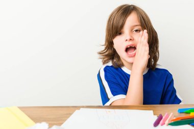 Küçük çocuk resim ve masasında ödevleri yapıyor gizli bir sıcak fren haber söylüyor ve kenara bakıyor