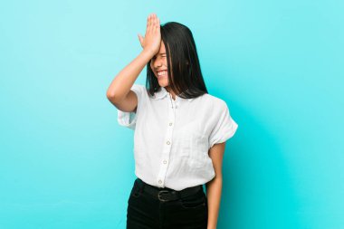 Bir şey unutmadan mavi bir duvara karşı Genç İspanyol serin kadın, avuç içi ve kapanış gözleri ile alnına tokat.