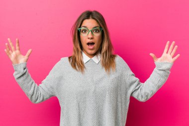 Hoş bir sürpriz alan bir duvara karşı genç otantik karizmatik gerçek insanlar kadın, heyecanlı ve ellerini yükselterek.