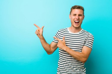 Mavi duvara karşı genç beyaz adam bir fotokopi alanı için işaret eden, heyecan ve arzu ifade.