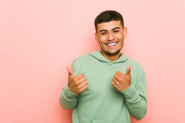 Genç İspanyol spor adam, gülümseyerek ve kendinden emin her iki başparmak yükselterek.