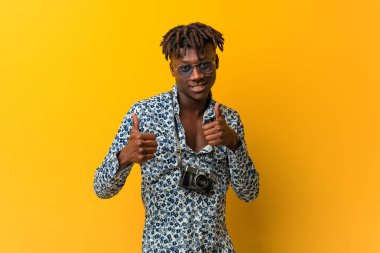 Genç siyah rasta adam bir tatil bakmak, gülümseyerek ve kendinden emin, her iki başparmak yükselterek.