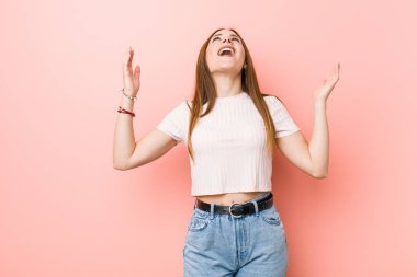 Genç kızıl saçlı zencefil kadın gökyüzüne çığlık pembe bir duvara karşı, yukarı bakıyor, sinirli.