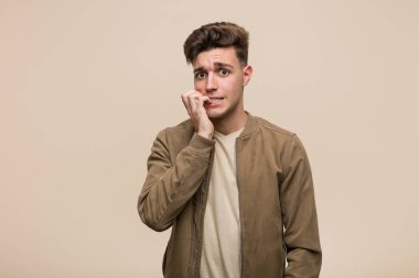 Kahverengi bir ceket giyen, tırnaklarını ısıran genç beyaz adam, sinirli ve çok endişeli.