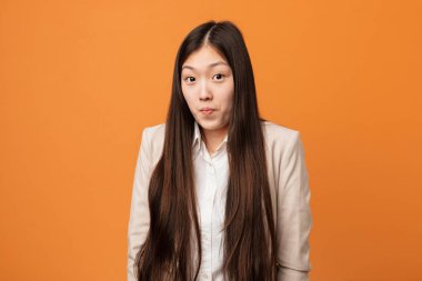 Genç iş Çinli kadın omuz silkiyor ve açık gözleri karıştı.