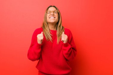 Genç otantik karizmatik gerçek insanlar kadın bir duvara karşı yumruk yükselterek, mutlu ve başarılı hissediyorum. Zafer kavramı.