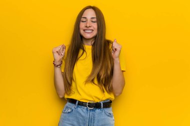 Genç kızıl kızıl saçlı kadın yumruk yükselterek, mutlu ve başarılı hissediyorum. Zafer kavramı.