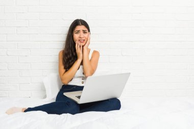 Genç Arap kadın yatakta onun laptop ile çalışan sızlanan ve disconsolately ağlıyor.