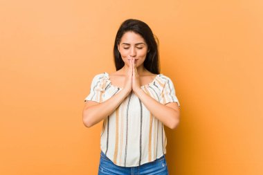 Genç kıvrımlı kadın ağız yakınında dua el ele tutuşarak, kendinden emin hissediyor.