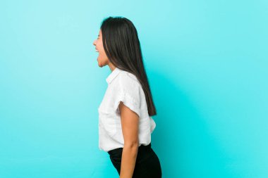 Mavi bir duvara karşı genç İspanyol serin kadın bir kopya alanı doğru bağırarak