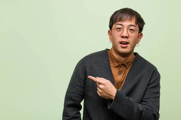 Young chinese man against a green wall — Stock Photo, Image