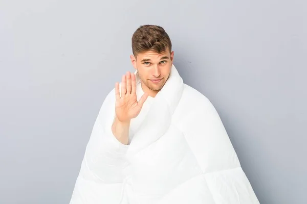 Young Man Holding Nordic Duvet Standing Outstretched Hand Showing Stop — Stock Photo, Image