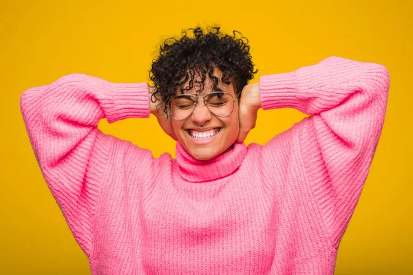 耳を覆うピンクのセーターを着た若いアフリカ系アメリカ人女性は あまりにも大きな音を聞かないようにしようとする — ストック写真