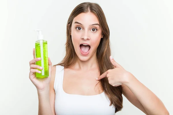Young Caucasian Woman Holding Aloe Vera Bottle Surprised Pointing Himself — Stock fotografie