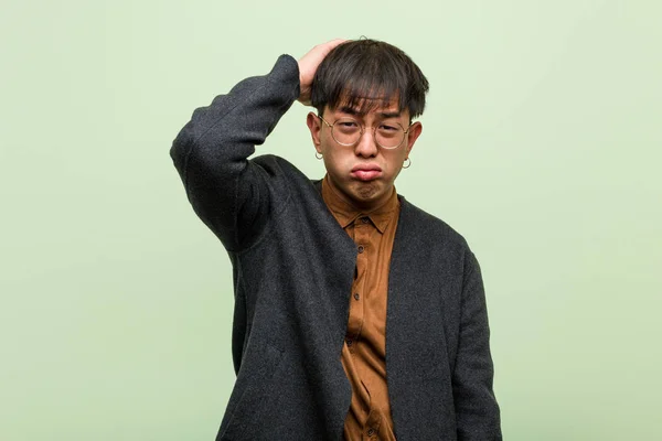 Mladý čínský muž proti zelené stěně — Stock fotografie