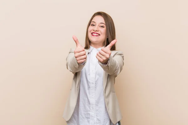 Young business woman with thumbs ups, cheers about something, support and respect concept.