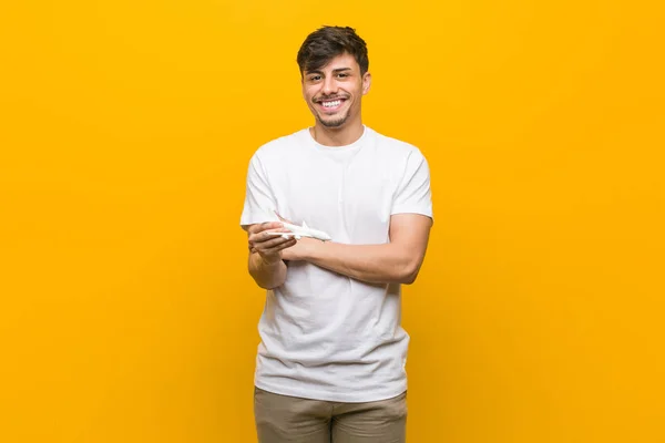 Joven Hispano Sosteniendo Icono Avión Sonriendo Confiado Con Los Brazos —  Fotos de Stock