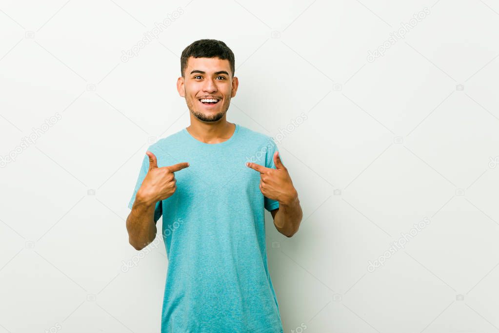 Young hispanic man surprised pointing with finger, smiling broadly.