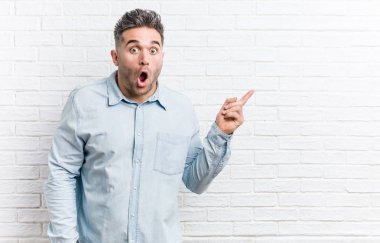 Yan gösteren bir tuğla duvara karşı genç yakışıklı adam