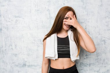 Genç fitness kadın parmakları ile kamera göz kırpma, utanç yüzü kapsayan.