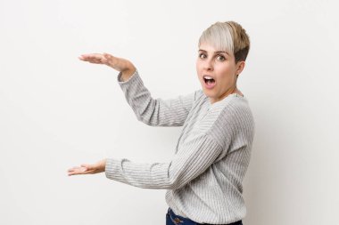 Genç kıvrımlı beyaz kadın beyaz arka plan izole şok ve elleri arasında bir kopya alanı tutarak şaşırdı.