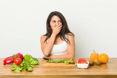 Genç kıvrımlı kadın el ile ağız kapsayan bir kopyasını alan arayan sağlıklı bir yemek düşünceli hazırlanıyor.