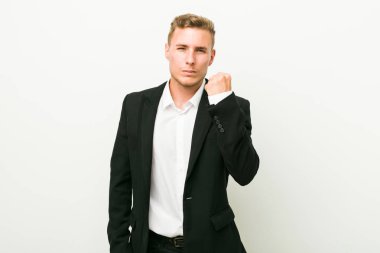 Genç beyaz iş adamı kameraya yumruk gösteren, agresif yüz ifadesi.