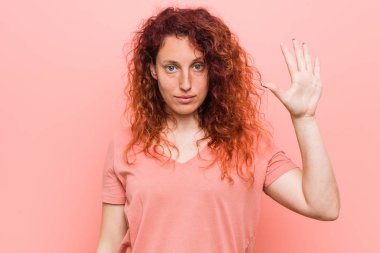 Genç doğal ve otantik kızıl saçlı kadın gülümseyen neşeli parmakları ile beş numara gösteren.