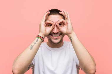 Genç rahat adam gözleri üzerinde tamam işareti gösteren