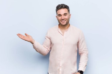 Genç yakışıklı serin adam bir avuç üzerinde bir kopya alanı gösteren ve bel başka bir el tutarak.