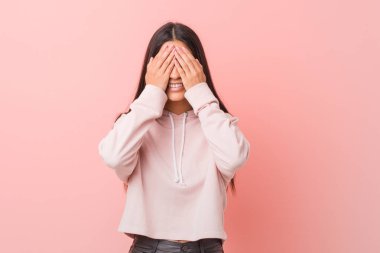 Rahat bir spor bakmak giyen genç güzel Arap kadın elleri ile gözleri kaplar, geniş bir sürpriz bekliyor gülümsüyor.